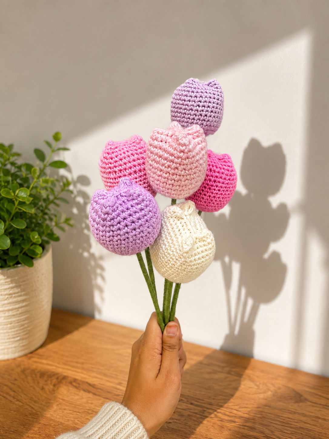 Set of 6 multicoloured handmade crochet tulips in pastel pink, lavender, ivory and bright pink shades, arranged as a bouquet with green stems.