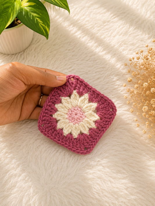 Handmade daisy-inspired crochet coaster featuring pink and ivory floral detailing crafted from premium cotton yarn by The Hook Project.