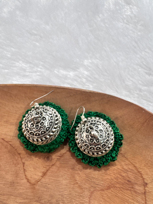 Handmade Noor crochet statement earrings featuring intricate silver-tone metalwork with emerald green crochet detailing.