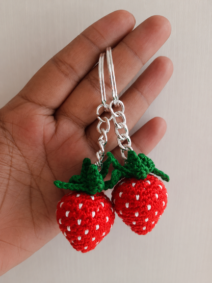 Handcrafted crochet strawberry keychain with embroidered white seeds and green leaves attached to a metal keyring by The Hook Project