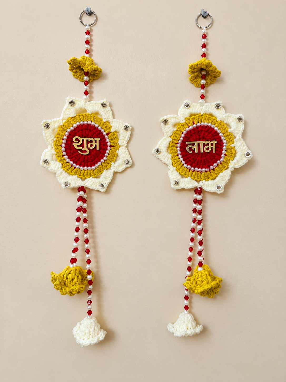 Shubh Labh Marigold crochet wall hanging set of 2 in red, mustard yellow and ivory with gold Hindi lettering, pearl-like details and beaded crochet tassels.