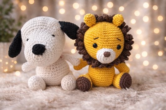 Handmade crochet lion and puppy toy set sitting together on a soft cream background with warm decorative lights.