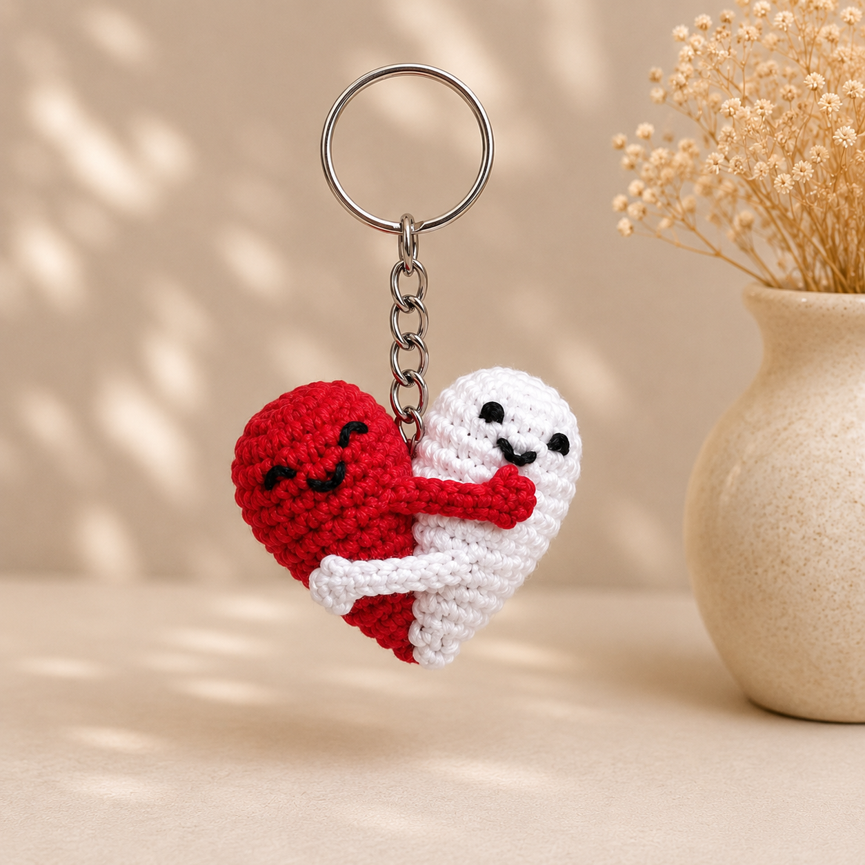 Handmade crochet keychain featuring red and white hugging hearts attached to a metal keyring.