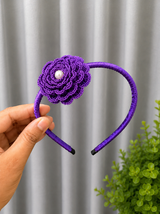 Handmade royal violet crochet floral headband featuring a layered flower with pearl center on a satin-wrapped headband.