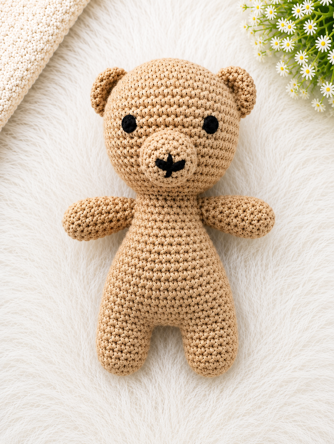 Handmade beige crochet teddy bear soft toy crafted from cotton yarn, displayed on a soft white fur background.