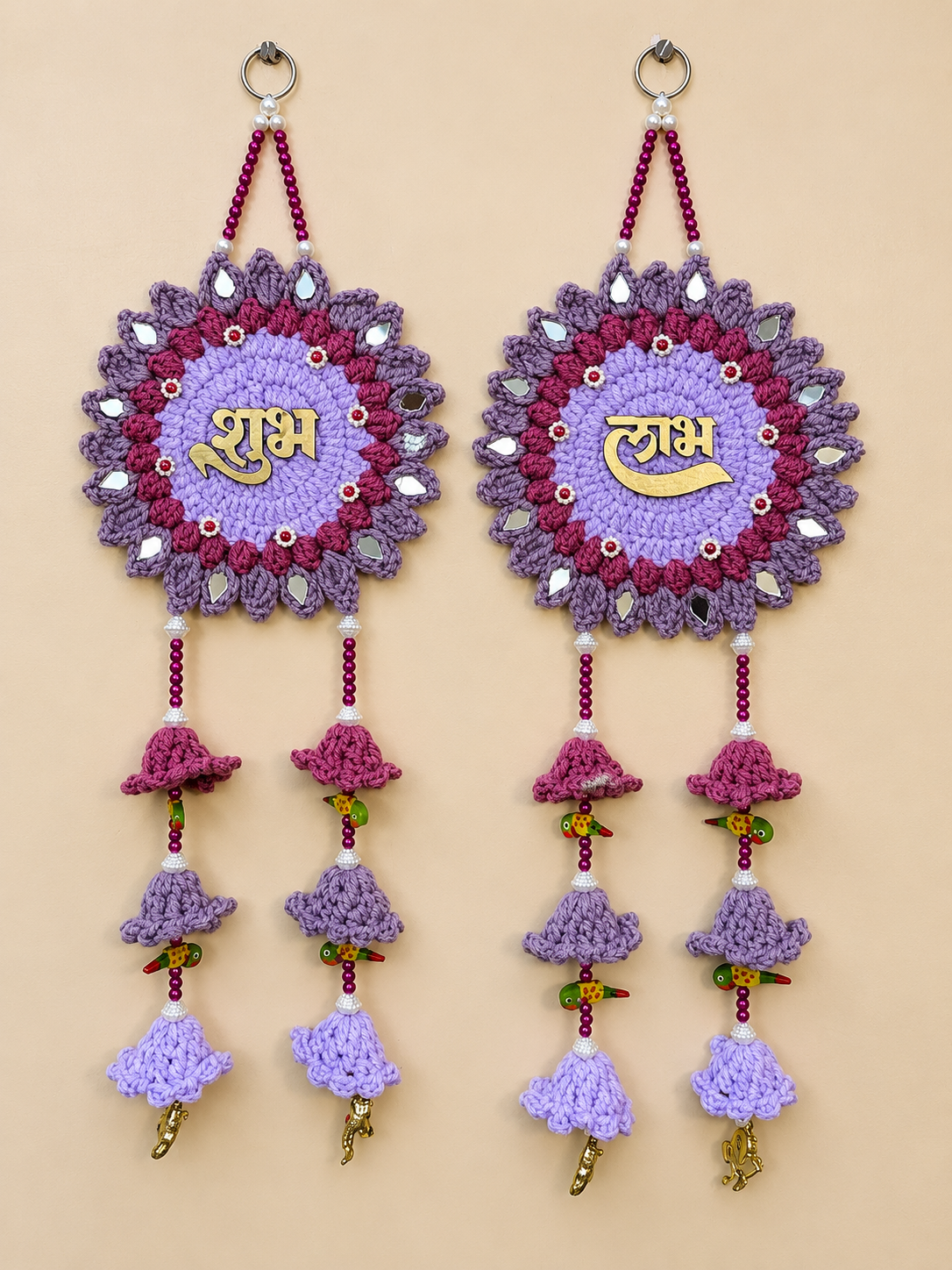 Shubh Labh lavender crochet wall hanging set of 2 with gold Hindi lettering, purple floral motifs, reflective accents, magenta beads and layered crochet bell tassels.