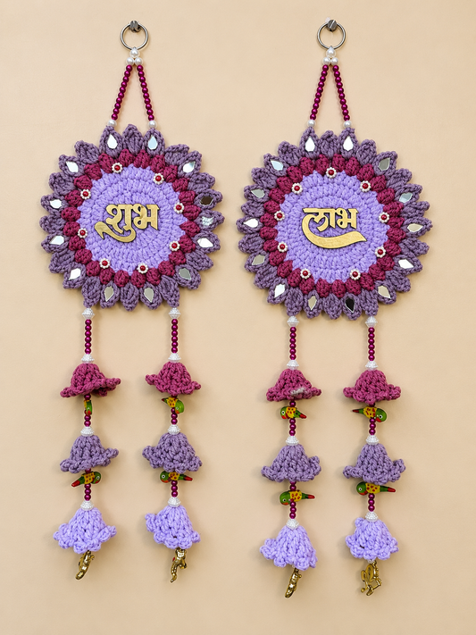 Shubh Labh lavender crochet wall hanging set of 2 with gold Hindi lettering, purple floral motifs, reflective accents, magenta beads and layered crochet bell tassels.