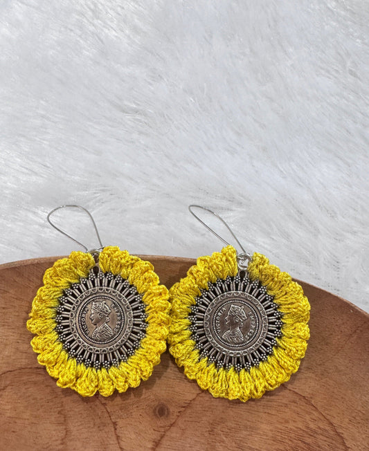 Handmade Aarohi crochet coin earrings in mustard yellow featuring a vintage coin-inspired oxidized metal centerpiece.